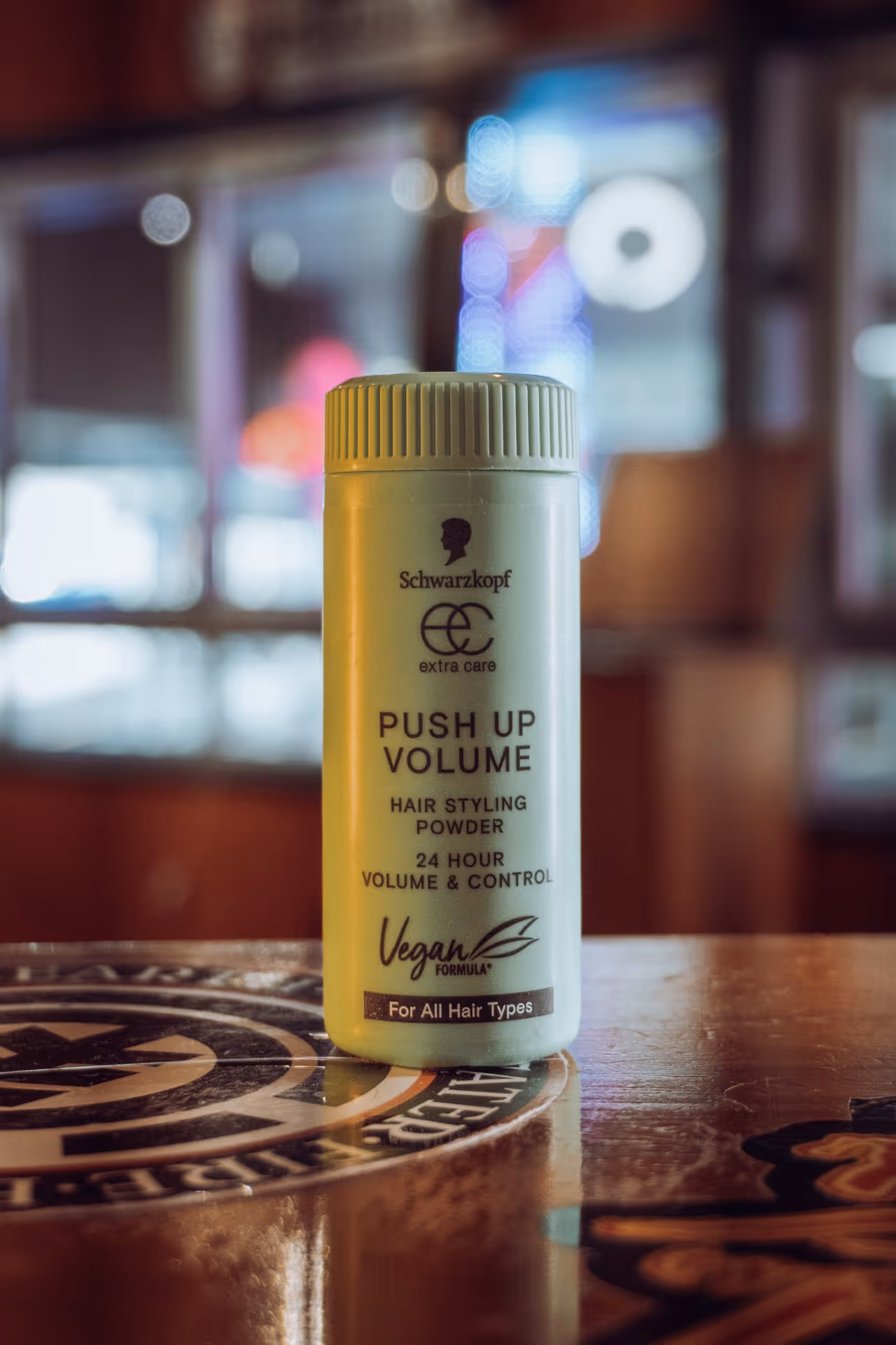 Bottle of Schwarzkopf Push Up Volume hair styling powder with vegan formula on a wooden table.
